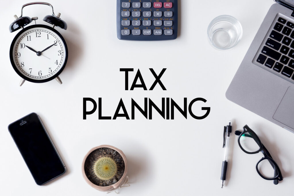 A phone, clock, calculator, glasses, and other items on a white background with the words “TAX PLANNING” in El Paso.