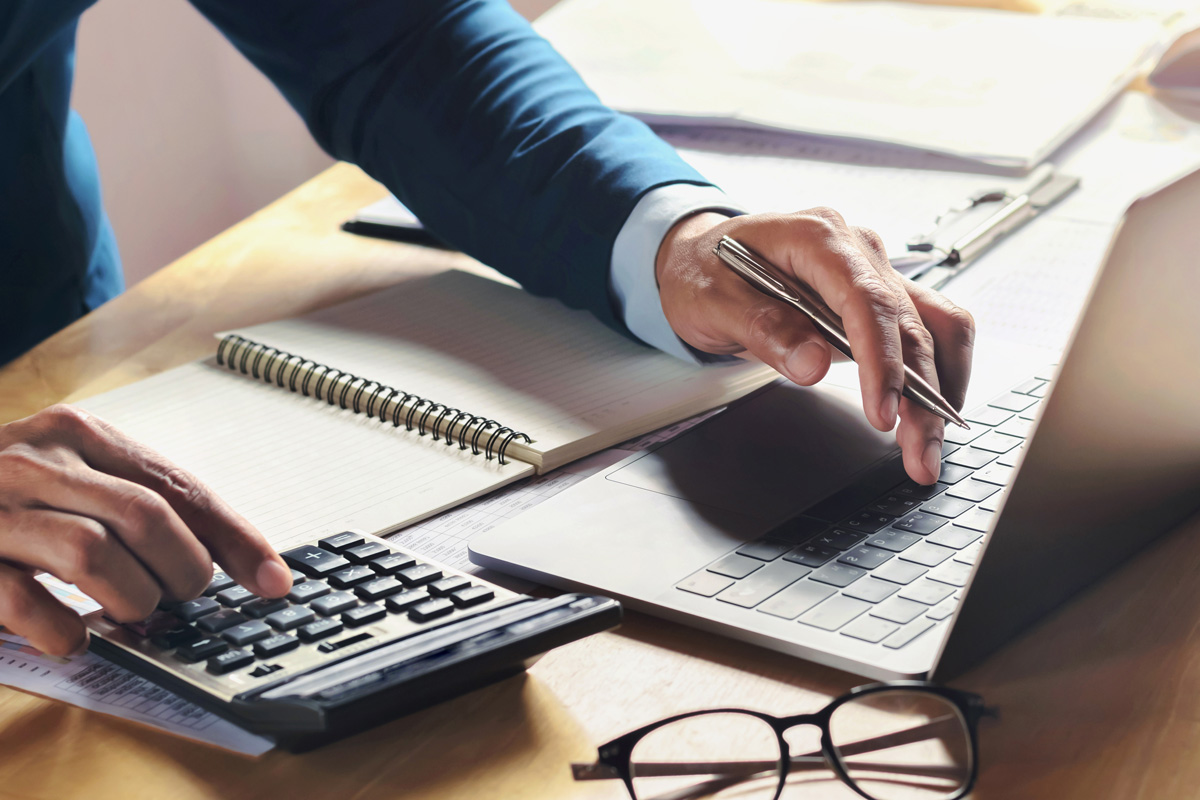 A person using a computer and calculator for their small business accounting in El Paso.