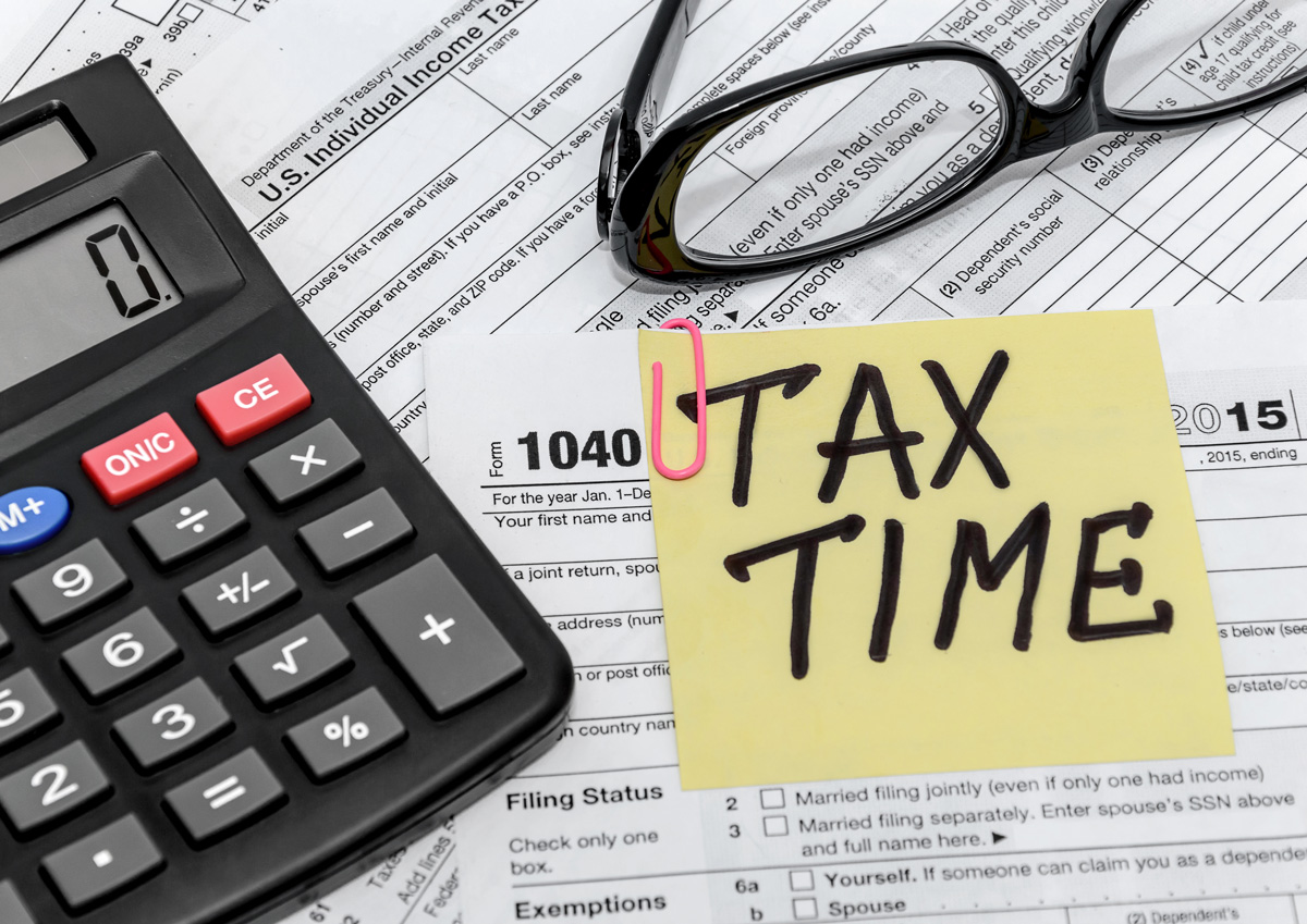 A calculator and a yellow sticky note on top of tax documents in El Paso.