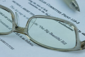 A pair of glasses on top of a piece of paper that reads “One Big Beautiful Bill”.