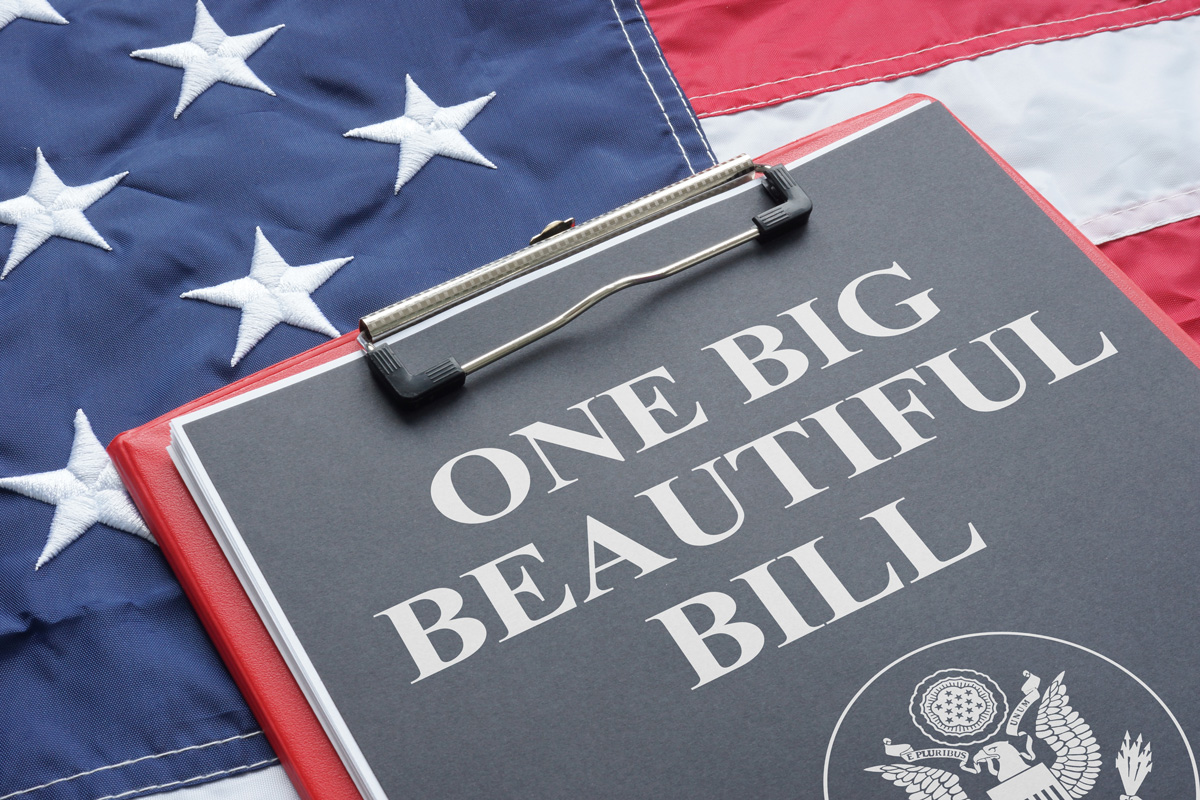 A clipboard with a black piece of paper that says “ONE BIG BEAUTIFUL BILL” on top of an American flag.